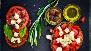 A vibrant Greek salad featuring tomatoes, feta, and olives on a slate board, perfect for healthy eating.